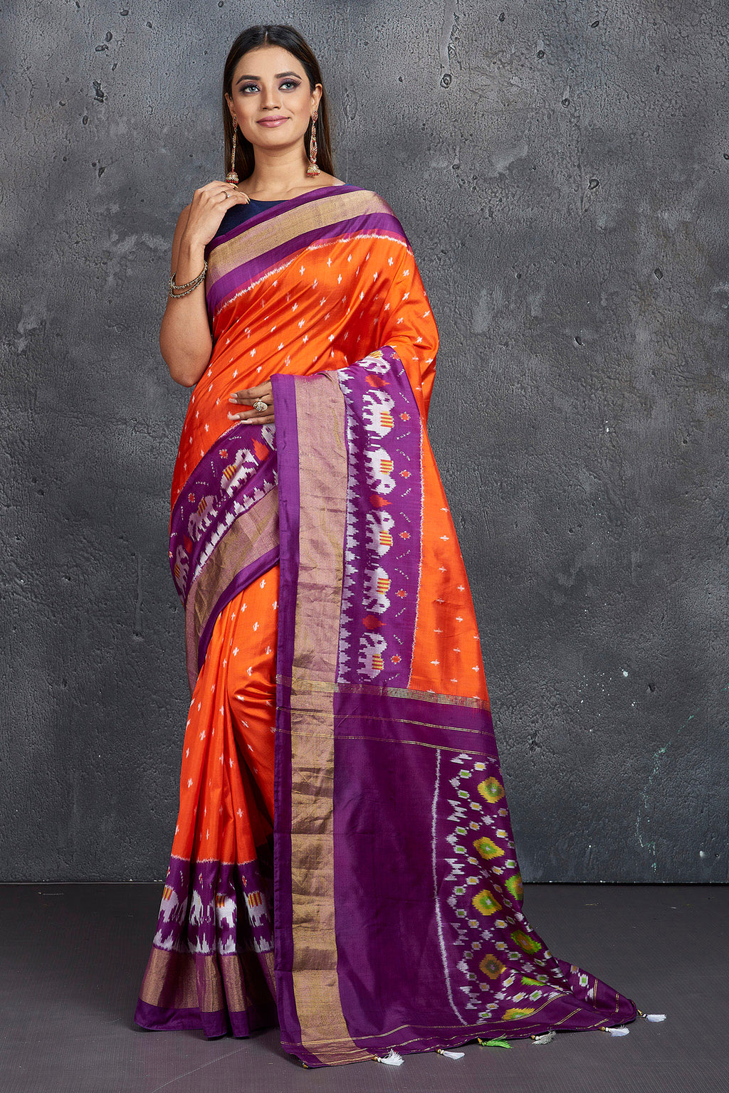 Shop beautiful orange ikkat silk saree online in USA with purple zari border. Keep your ethnic wardrobe up to date with latest designer sarees, pure silk sarees, Kanchipuram silk sarees, handwoven sarees, tussar silk sarees, embroidered sarees from Pure Elegance Indian saree store in USA.-full view