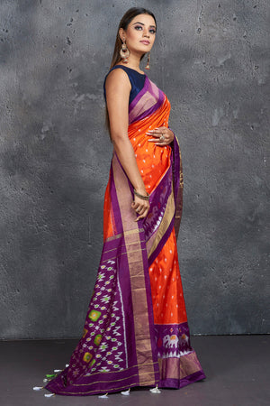 Shop beautiful orange ikkat silk saree online in USA with purple zari border. Keep your ethnic wardrobe up to date with latest designer sarees, pure silk sarees, Kanchipuram silk sarees, handwoven sarees, tussar silk sarees, embroidered sarees from Pure Elegance Indian saree store in USA.-side