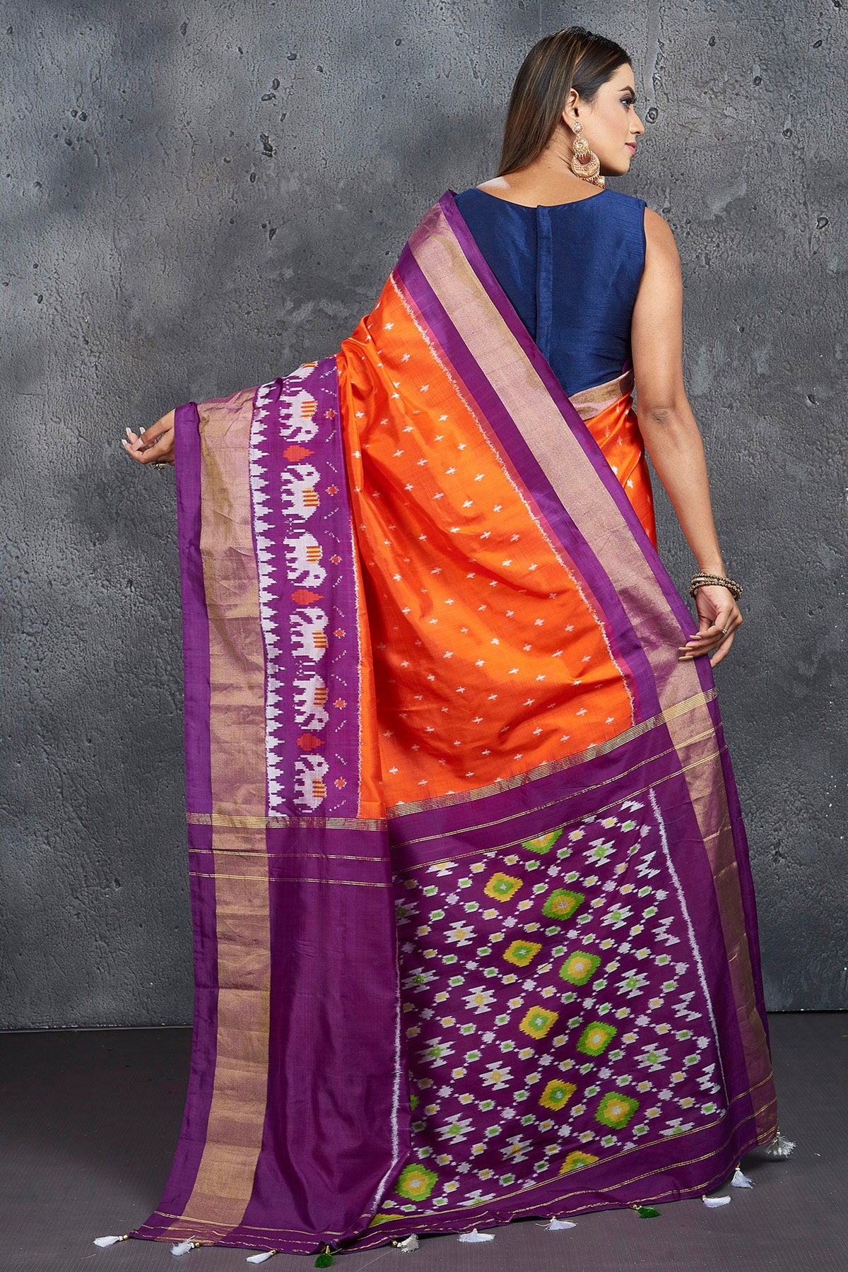 Shop beautiful orange ikkat silk saree online in USA with purple zari border. Keep your ethnic wardrobe up to date with latest designer sarees, pure silk sarees, Kanchipuram silk sarees, handwoven sarees, tussar silk sarees, embroidered sarees from Pure Elegance Indian saree store in USA.-back