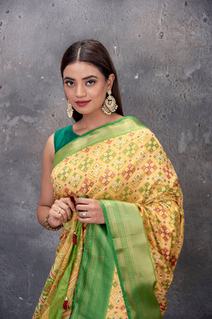 Buy gorgeous yellow printed fancy Patola sari online in USA with green zari border. Keep your ethnic wardrobe up to date with latest designer saris, pure silk sarees, handwoven sarees, tussar silk sarees, embroidered saris from Pure Elegance Indian saree store in USA.-closeup