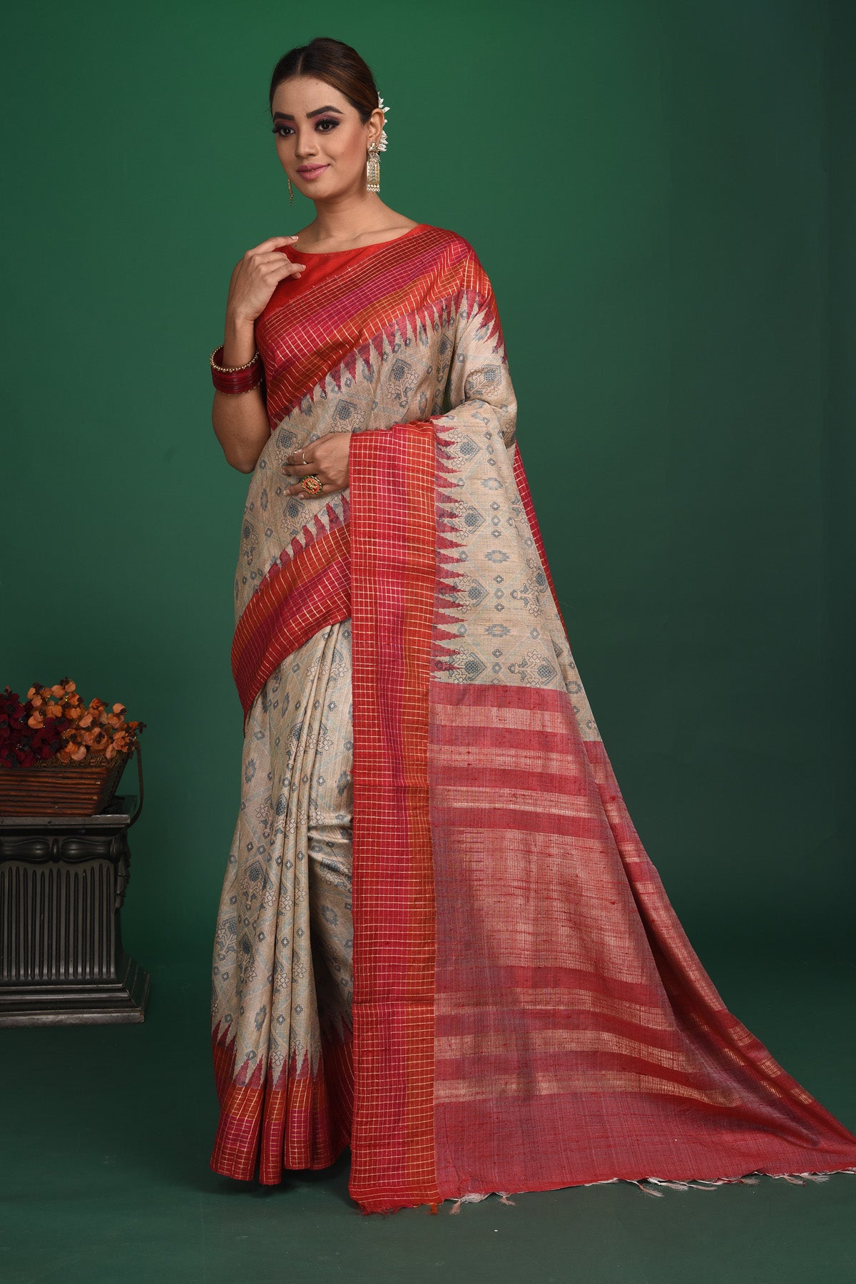 Shop this exquisite beige tussar saree with red vidharbha and zari border online in USA which is handcrafted from fine silk tussar fabric, this tie and dye saree brings out the nature of flow. This tussar saree with elegant red Vidharbha border is making everyone swoon over it. Make it yours and flaunt a handwoven marvel with minimal jewellery for a casual day outfit. Add this pure tussar saree to your collection from Pure Elegance Indian fashion store in USA.-Side view with open pallu.