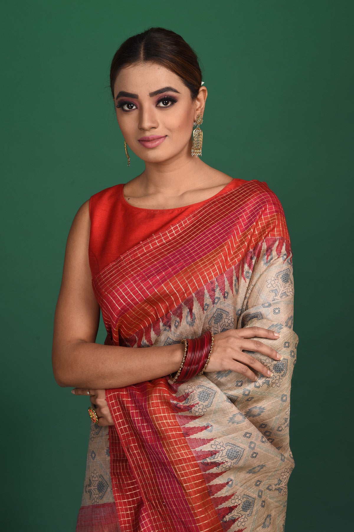 Shop this exquisite beige tussar saree with red vidharbha and zari border online in USA which is handcrafted from fine silk tussar fabric, this tie and dye saree brings out the nature of flow. This tussar saree with elegant red Vidharbha border is making everyone swoon over it. Make it yours and flaunt a handwoven marvel with minimal jewellery for a casual day outfit. Add this pure tussar saree to your collection from Pure Elegance Indian fashion store in USA.-Close up.