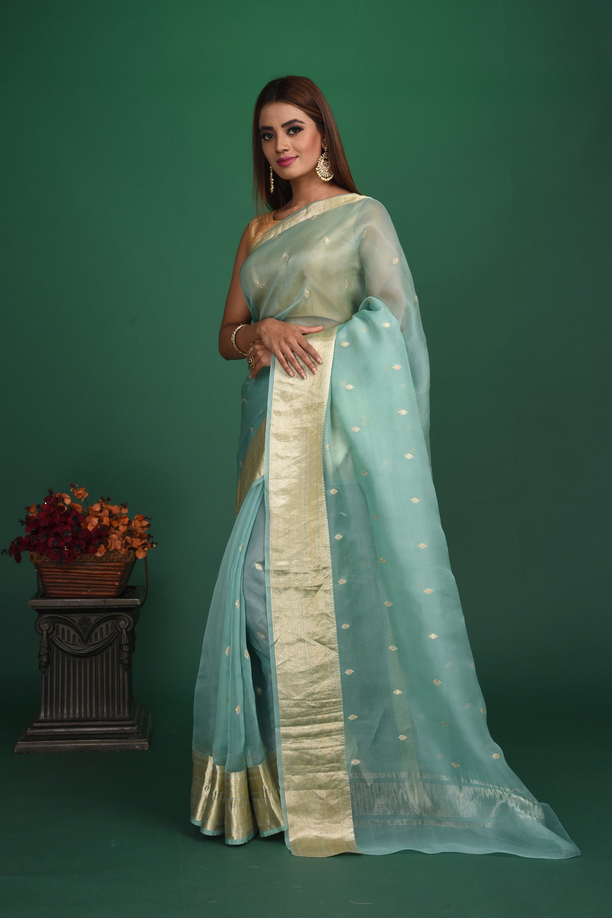 Shop this elegant firozi blue soft organza designer saree with dull gold zari work on heavy border online in USA. Organza silk fabric is a type of silk cloth that is crisp, translucent, and extremely light in weight. It is used to make organza silk saree, drapes, and other decorative pieces. Add this designer sari to your collection from Pure Elegance Indian fashion store in USA.-Side view with open pallu.