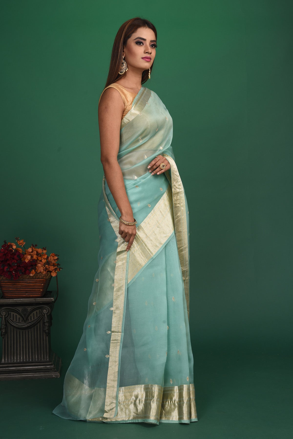 Shop this elegant firozi blue soft organza designer saree with dull gold zari work on heavy border online in USA. Organza silk fabric is a type of silk cloth that is crisp, translucent, and extremely light in weight. It is used to make organza silk saree, drapes, and other decorative pieces. Add this designer sari to your collection from Pure Elegance Indian fashion store in USA.-Side view.