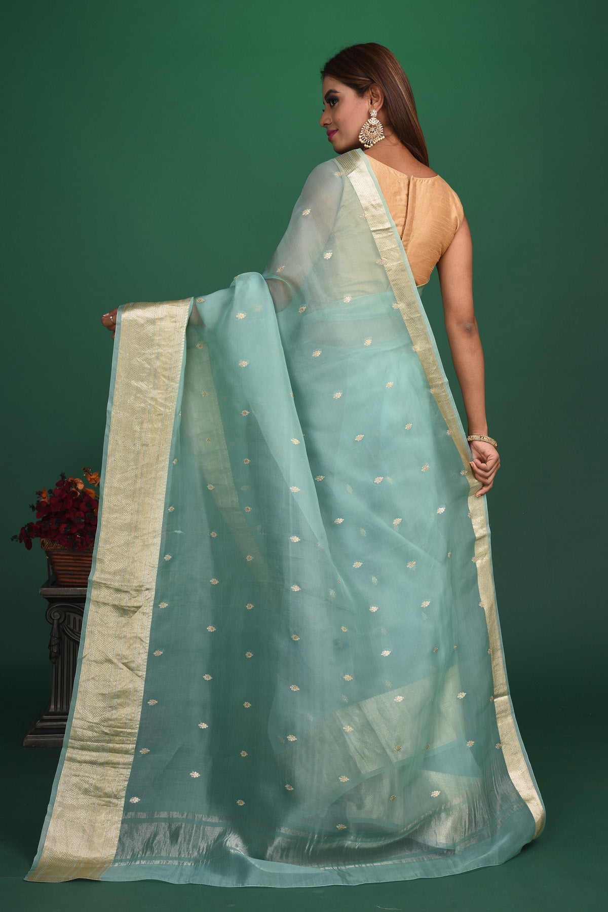 Shop this elegant firozi blue soft organza designer saree with dull gold zari work on heavy border online in USA. Organza silk fabric is a type of silk cloth that is crisp, translucent, and extremely light in weight. It is used to make organza silk saree, drapes, and other decorative pieces. Add this designer sari to your collection from Pure Elegance Indian fashion store in USA.-Back view with open pallu.