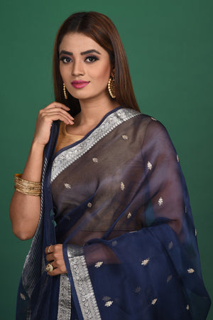 Buy this elegant dark blue soft organza designer saree with silver zari work on heavy border online in USA. Organza silk fabric is a type of silk cloth that is crisp, translucent, and extremely light in weight. It is used to make organza silk saree, drapes, and other decorative pieces. Add this designer sari to your collection from Pure Elegance Indian fashion store in USA.-Close up.