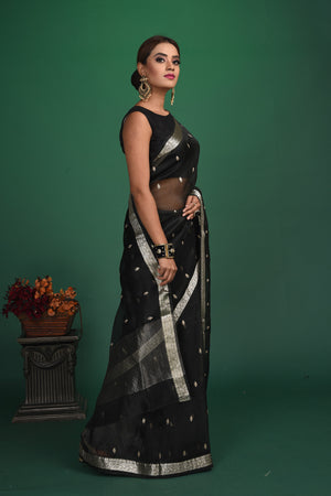 Buy this elegant black soft organza designer saree with silver zari work on heavy border online in USA. Organza silk fabric is a type of silk cloth that is crisp, translucent, and extremely light in weight. It is used to make organza silk saree, drapes, and other decorative pieces. Add this designer sari to your collection from Pure Elegance Indian fashion store in USA.-Side view.
