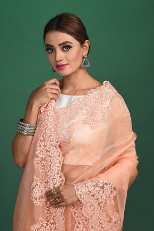 Shop this exquisite peach saree in soft organza with heavy lace border online in USA which is made of organza fabric and lightweight. This organza Saree is beautified with lace work and latest trend. Ideal for casual, kitty parties, stylish accessories. Shop this from Pure Elegance Indian fashion store in USA.-Close up.