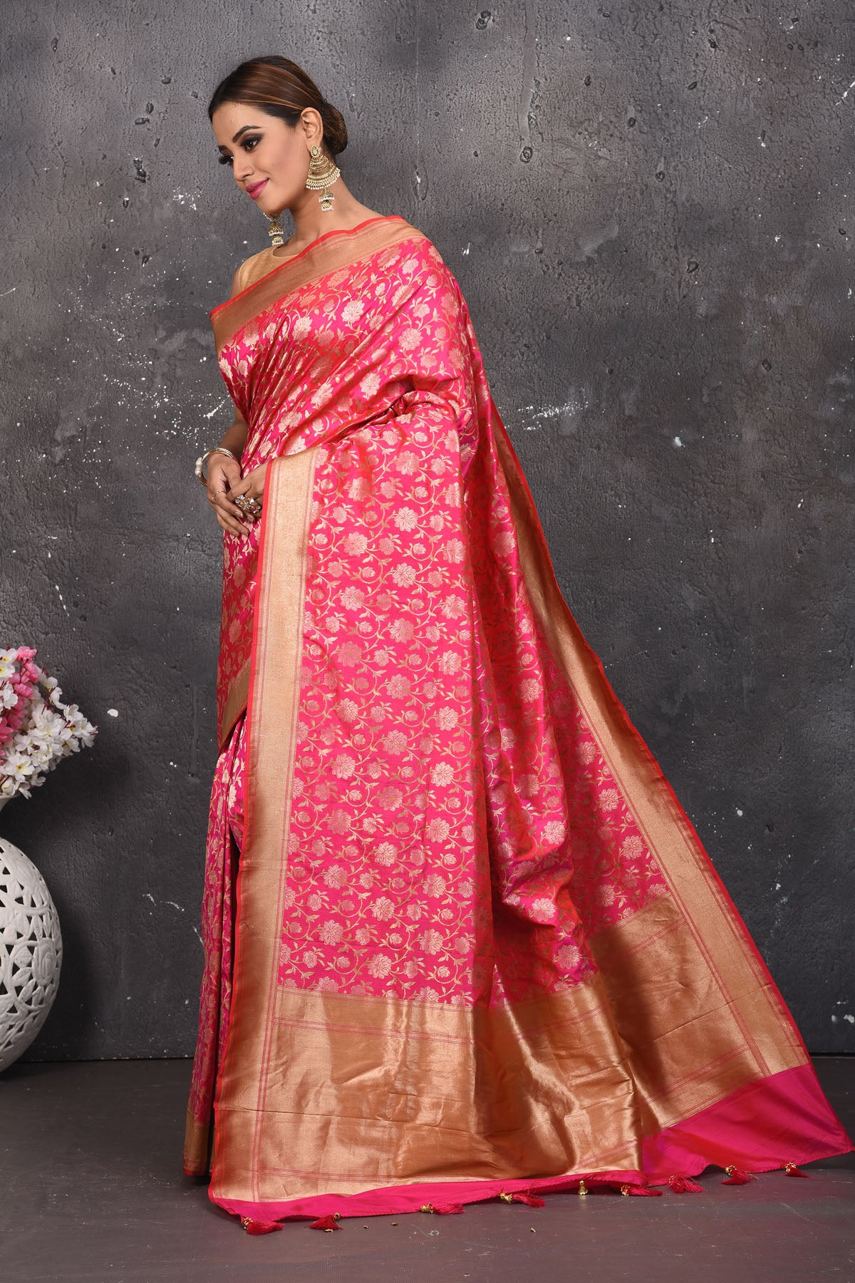Shop thos elegant pink woven banarasi silk saree with golden zari work online in USA. With exquisite design spread across the length of the saree, it is perfect for any occasion which has a beautiful floral pattern zari work with blend of gold colour. Pair this silk banarasi silk sari with heels and a moti necklace from Pure Elegance Indian fashion store in USA.- Full view with folded hands.