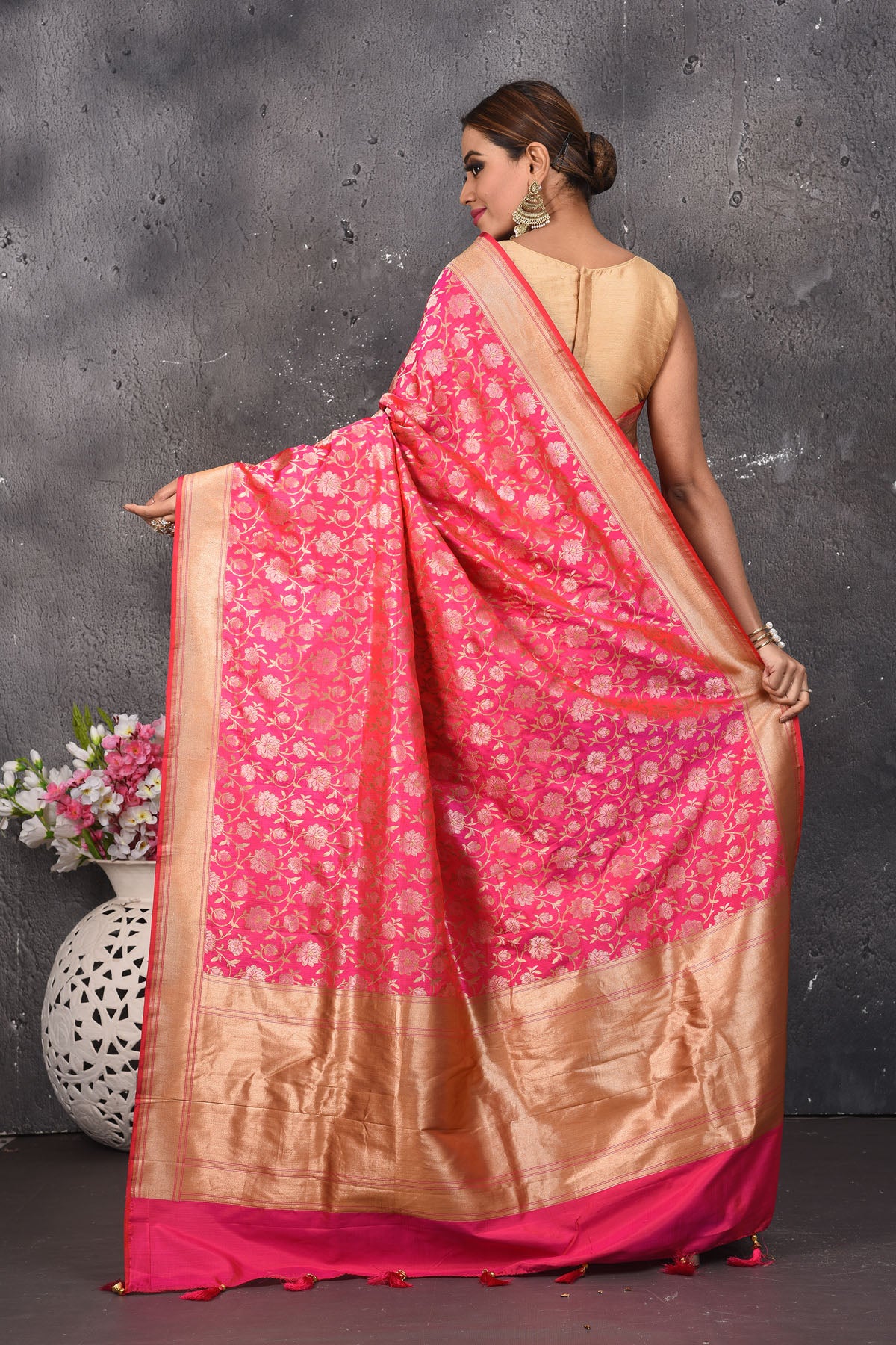 Shop thos elegant pink woven banarasi silk saree with golden zari work online in USA. With exquisite design spread across the length of the saree, it is perfect for any occasion which has a beautiful floral pattern zari work with blend of gold colour. Pair this silk banarasi silk sari with heels and a moti necklace from Pure Elegance Indian fashion store in USA.- Back view with open pallu.
