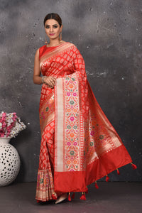 Shop this exquisite coral red silk brocade handloom banarasi saree online in USA. The sari comes with a graceful border with handmade latkan and colourful floral pattern all over. Buy this brocade banarsi sari with zari work from Pure Elegance Indian fashion store in USA and style it with your best pair of heels, gold or Moti necklace and a potli bag for the perfect look.- Full view with folded hands.