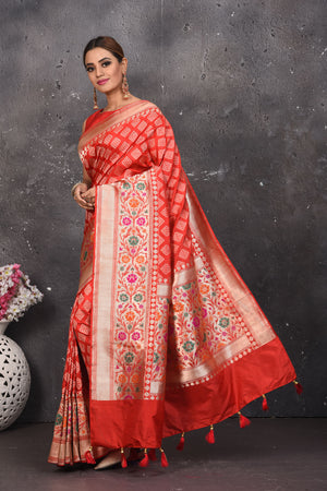 Shop this exquisite coral red silk brocade handloom banarasi saree online in USA. The sari comes with a graceful border with handmade latkan and colourful floral pattern all over. Buy this brocade banarsi sari with zari work from Pure Elegance Indian fashion store in USA and style it with your best pair of heels, gold or Moti necklace and a potli bag for the perfect look.- Side view with folded hands.