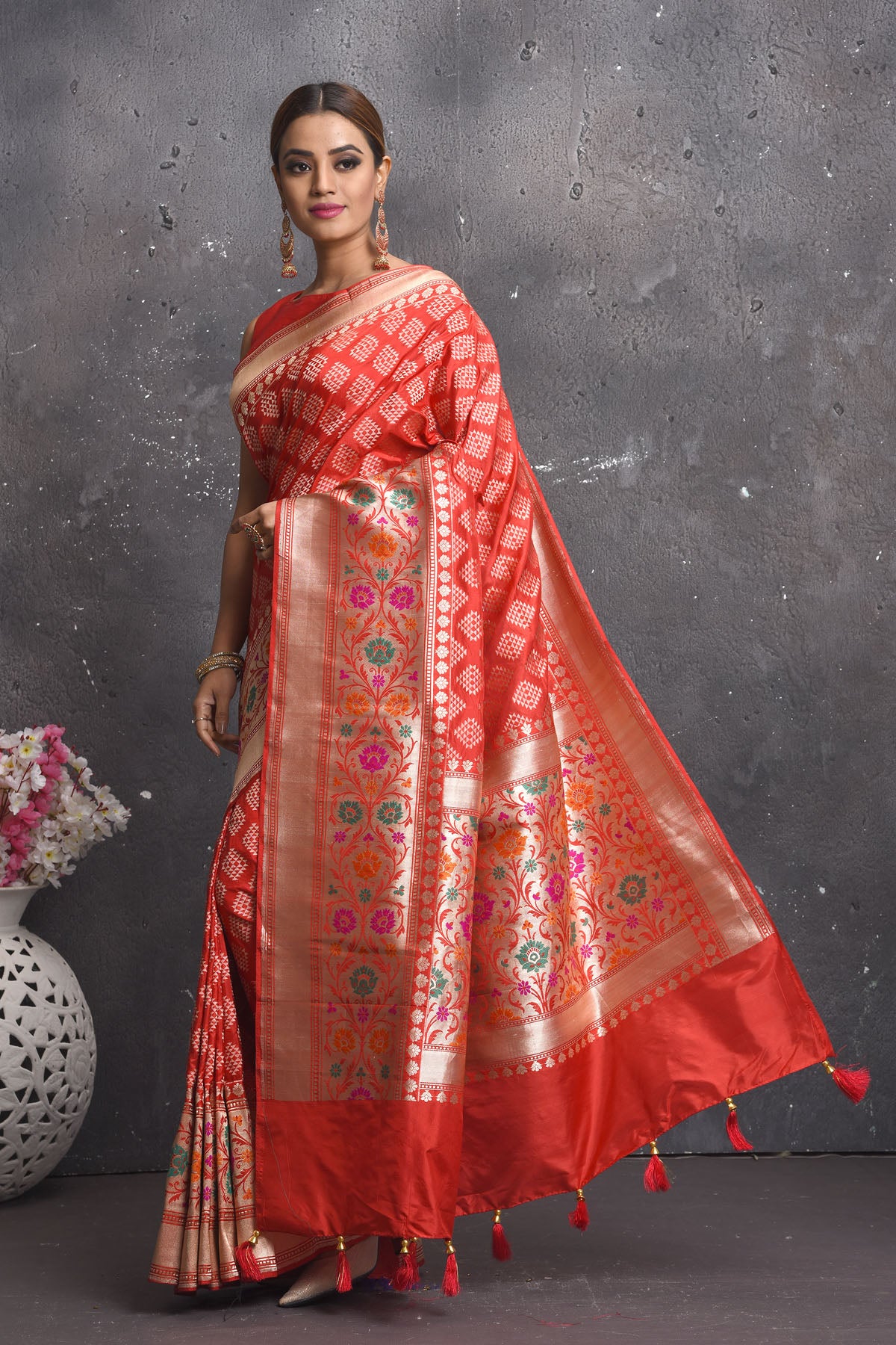 Shop this exquisite coral red silk brocade handloom banarasi saree online in USA. The sari comes with a graceful border with handmade latkan and colourful floral pattern all over. Buy this brocade banarsi sari with zari work from Pure Elegance Indian fashion store in USA and style it with your best pair of heels, gold or Moti necklace and a potli bag for the perfect look.- Side view with open pallu.