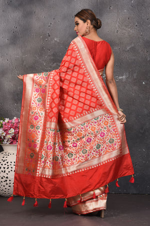 Shop this exquisite coral red silk brocade handloom banarasi saree online in USA. The sari comes with a graceful border with handmade latkan and colourful floral pattern all over. Buy this brocade banarsi sari with zari work from Pure Elegance Indian fashion store in USA and style it with your best pair of heels, gold or Moti necklace and a potli bag for the perfect look.- Back view with open pallu.