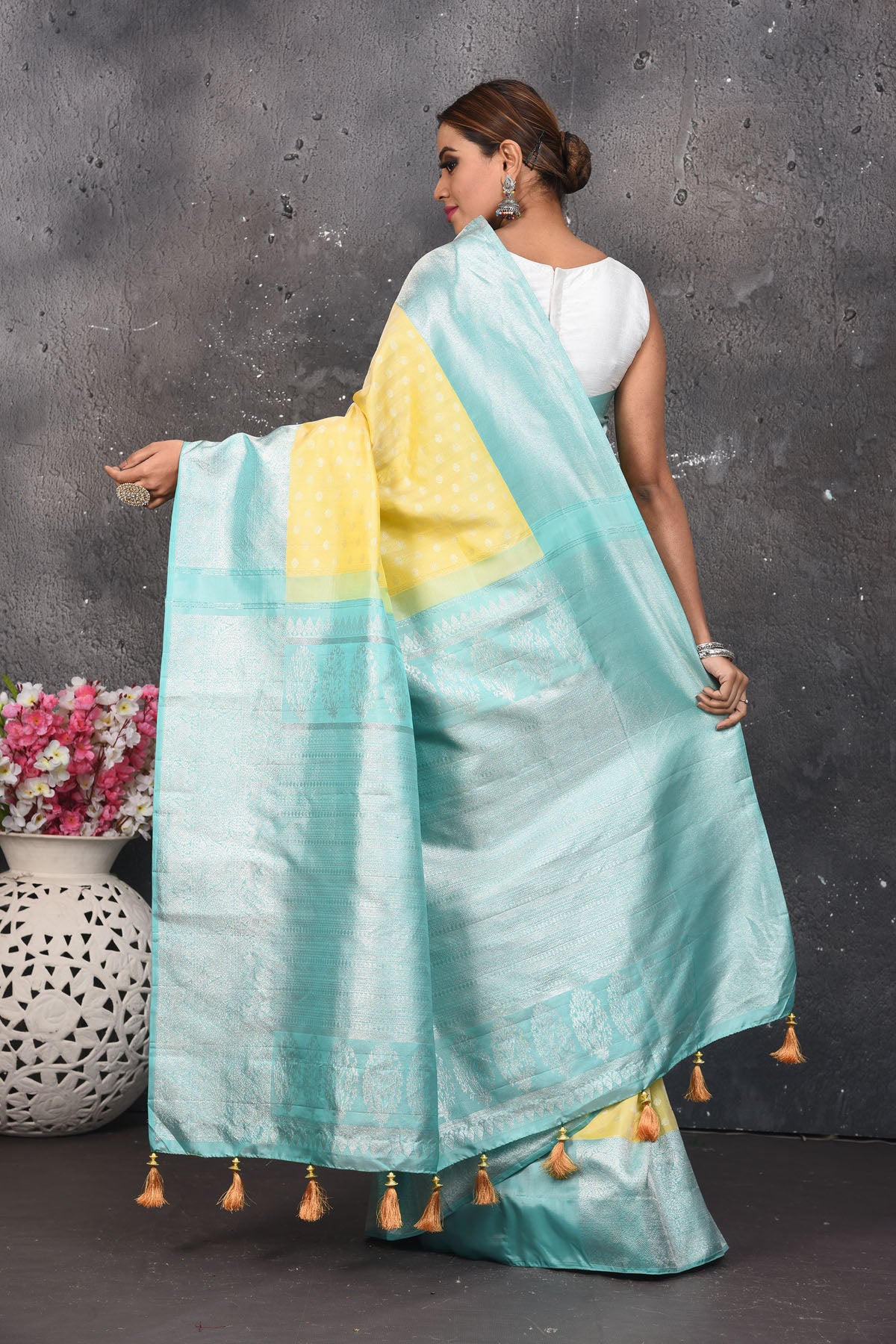 Shop this royal handwoven pure kanchiresham saree in lemon yellow with a firozi blue pallu and buti work online in USA. Presenting Enchanting Yet Breathable Organic Banarasi Saree Made from Kanjivaram silk. Drape yourself in this beautiful banarasi saree from Pure Elegance Indian Fashion Store in USA with Zari woven Border with a potli bag and high heels for a flawless look.- Back view with open pallu.