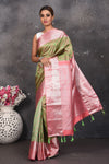 Buy this royal olive green-pink handloom kanchipuram saree with buta zari work online in USA. An enchanting silk saree with scintillating palla and border. This kanchipuram silk brings the charm and simplicity of this olive green saree with border and pallu with the delegate buta work with silver zari. Shop this designer silk sari from Pure Elegance Indian fashion store in USA.- Full view with folded hands.