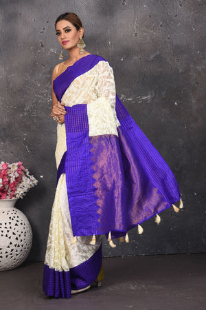 Buy this exquisite Off-white and violet chiffon box printed saree with chikankari hand-embroidered online in USA. Style this lucknawi sari with a potli bag and high heels for a flawless look which has gorgeous heavy pallu with dull-gold zari work. This saree is definitely the epitome of beauty and a must have in your collection. Buy designer handwoven chikankari sari with any blouse from Pure Elegance Indian saree store in USA.- Side view with folded hands.