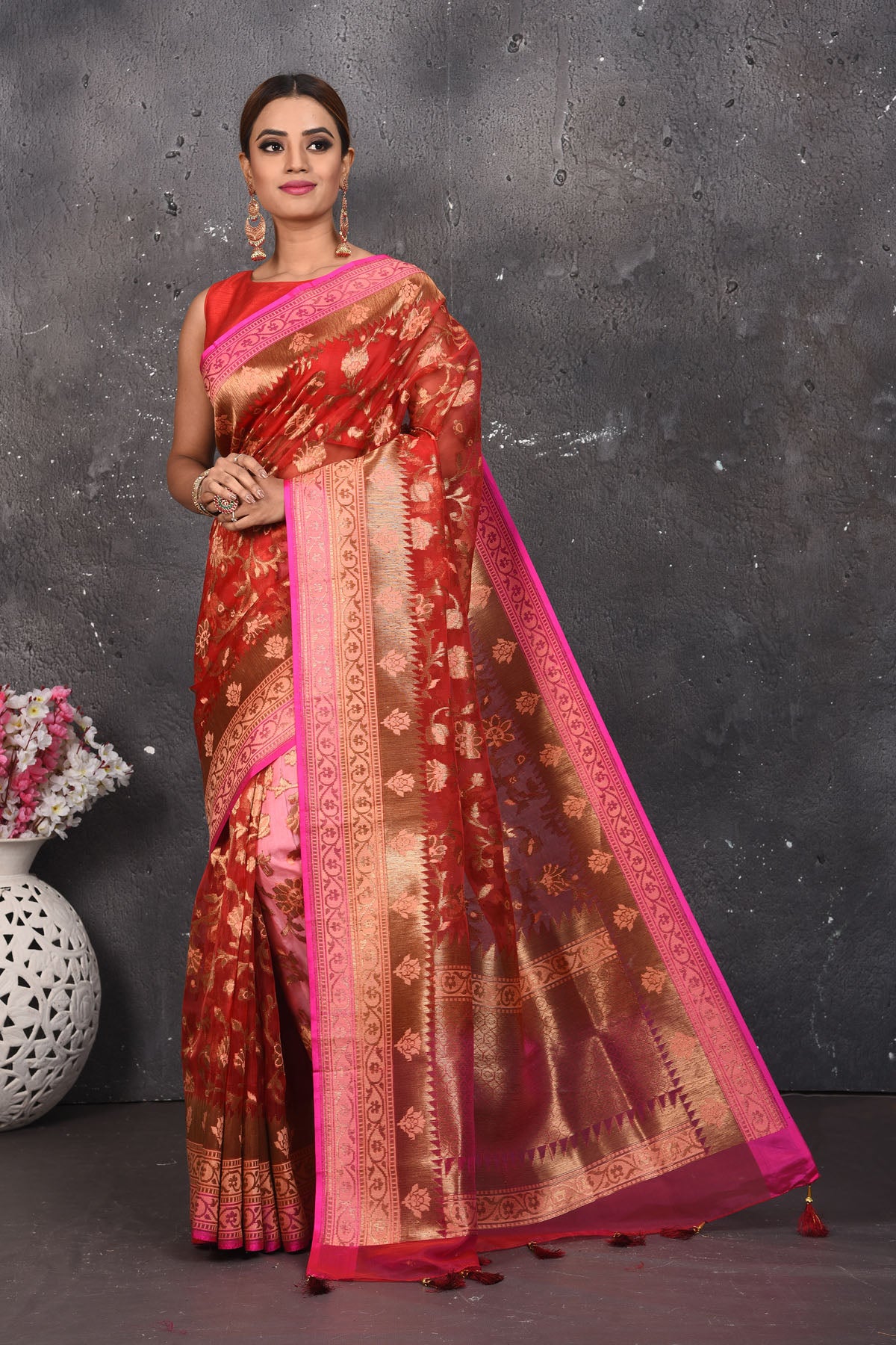 Buy this dazzling red kora silk handloom banarasi saree adorned with stunning resham and intricate Meenakari detailing along the border and pallu online in USA.  This Red color kora silk handloom Banarasi saree with pink-golden zari border in the comes with Unstitched blouse. Add this kora silk lace designer sari from Pure Elegance Indian fashion store in USA.- Full view with folded hands.