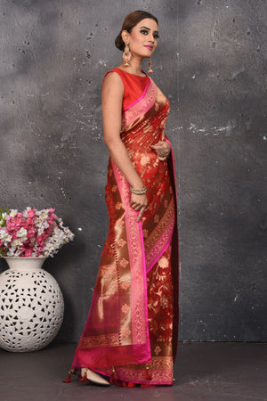 Buy this dazzling red kora silk handloom banarasi saree adorned with stunning resham and intricate Meenakari detailing along the border and pallu online in USA.  This Red color kora silk handloom Banarasi saree with pink-golden zari border in the comes with Unstitched blouse. Add this kora silk lace designer sari from Pure Elegance Indian fashion store in USA.- Side view.