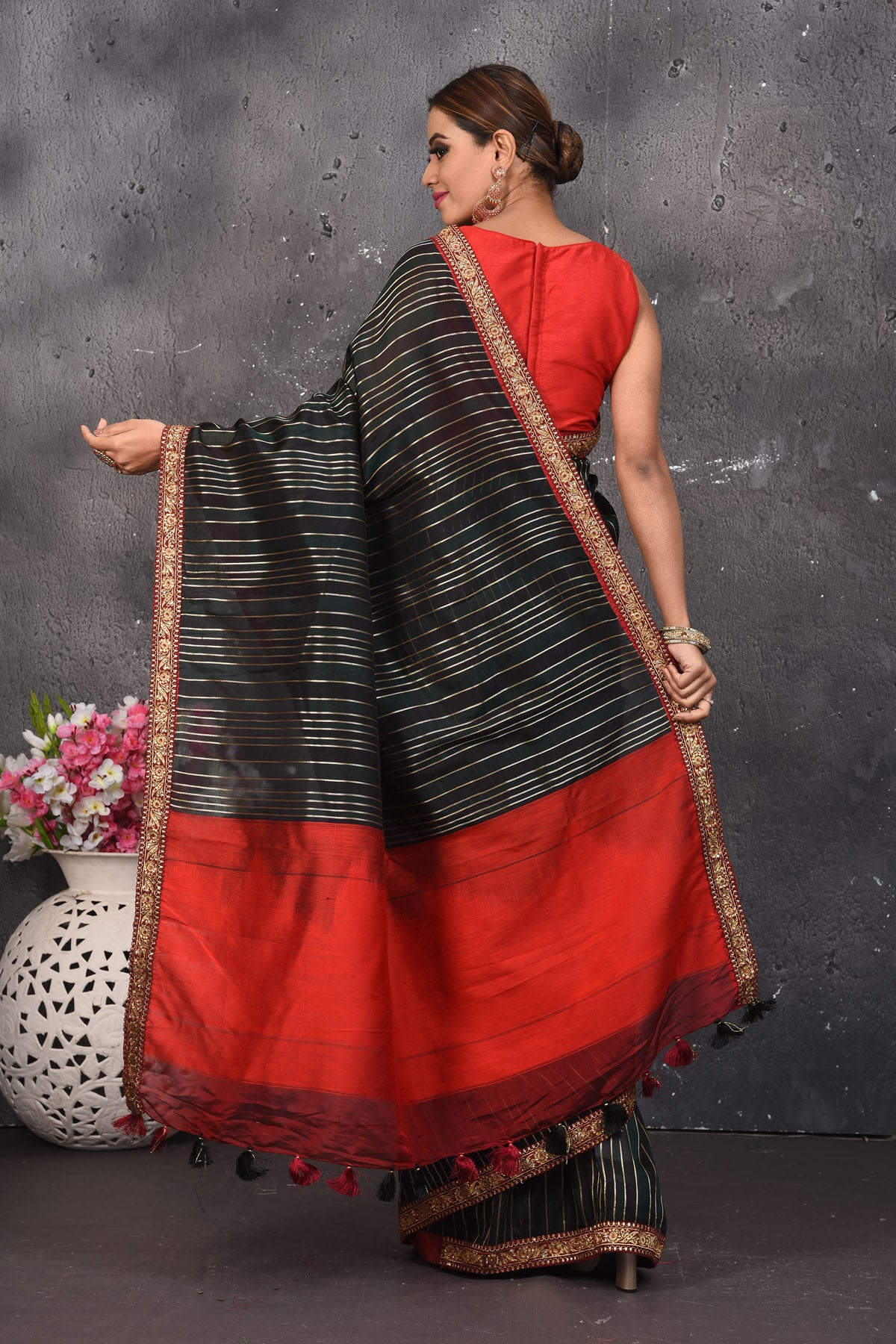 Buy this elegant black saree leheriya with gota patti work online in USA. Style this designer sari which has a beautiful red border with golden lace at the edge with a potli bag and high heels. Add designer gota patti sari to your collection from Pure Elegance Indian saree store in USA.- Back view with open pallu.