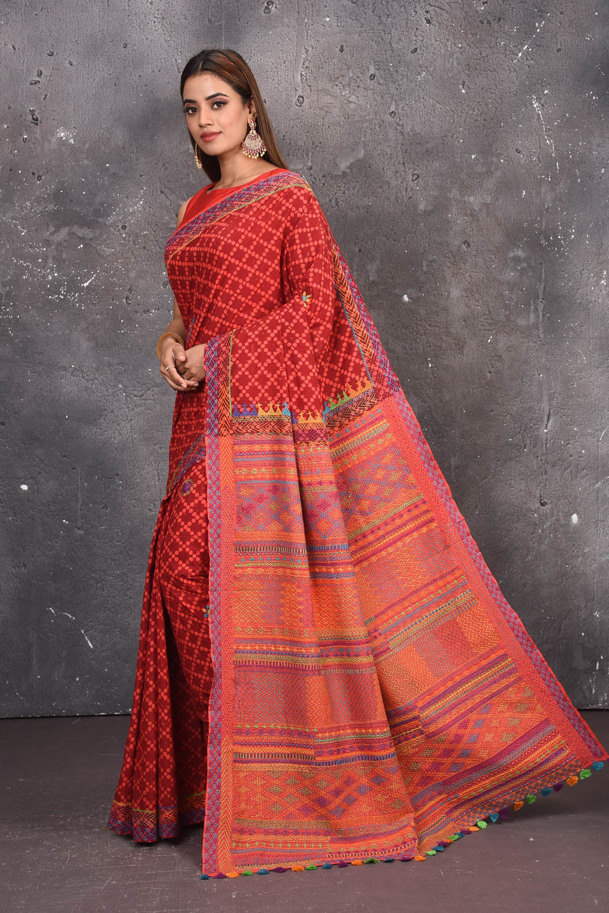 Shop this classy red hand painted madhubani cotton saree online in USA. Perfect to be worn as part of your everyday work wear, with this hand-painted red Madhubani saree, elegance meets traditional. Add this designer Lambani embroidery designer saree with colored tassels to your collection from Pure Elegance Indian Fashion Store in USA.- Side view with open pallu.