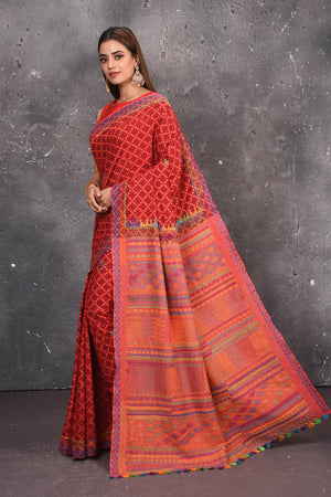 Shop this classy red hand painted madhubani cotton saree online in USA. Perfect to be worn as part of your everyday work wear, with this hand-painted red Madhubani saree, elegance meets traditional. Add this designer Lambani embroidery designer saree with colored tassels to your collection from Pure Elegance Indian Fashion Store in USA.- Side view with open pallu.