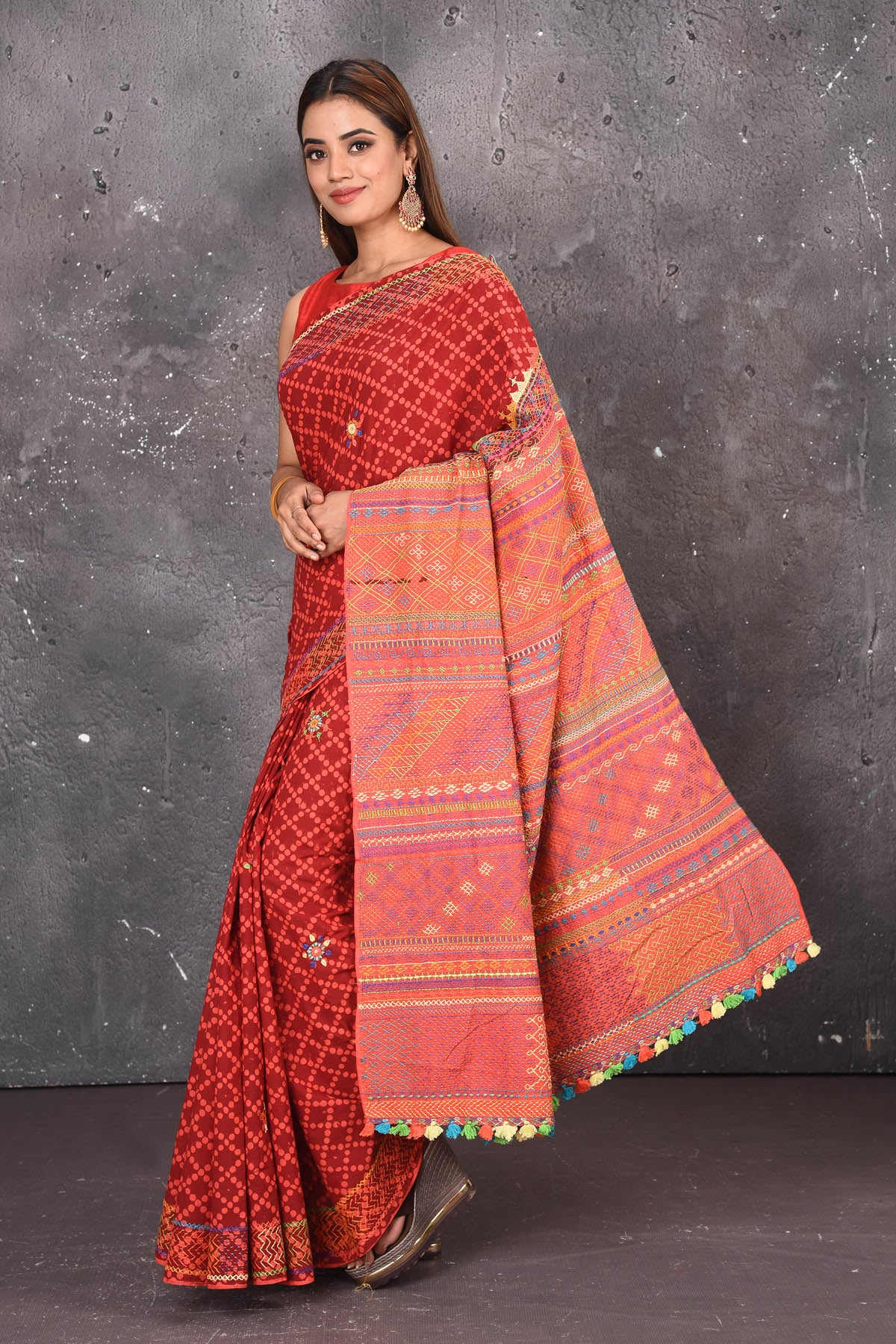 Shop this classy red hand painted madhubani cotton saree online in USA. Perfect to be worn as part of your everyday work wear, with this hand-painted red Madhubani saree, elegance meets traditional. Add this designer Lambani embroidery designer saree with colored tassels to your collection from Pure Elegance Indian Fashion Store in USA.- Full view with folded hands.
