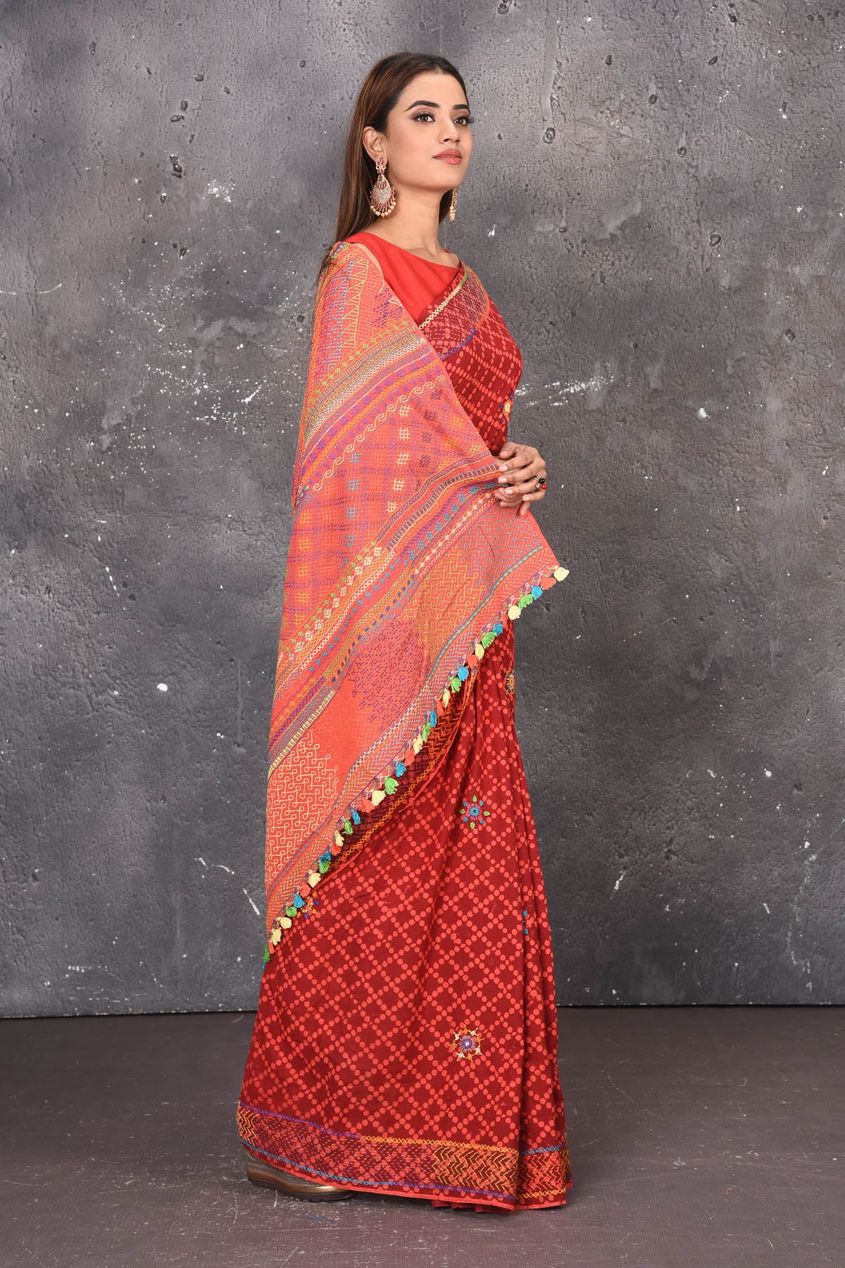 Shop this classy red hand painted madhubani cotton saree online in USA. Perfect to be worn as part of your everyday work wear, with this hand-painted red Madhubani saree, elegance meets traditional. Add this designer Lambani embroidery designer saree with colored tassels to your collection from Pure Elegance Indian Fashion Store in USA.- Side view.