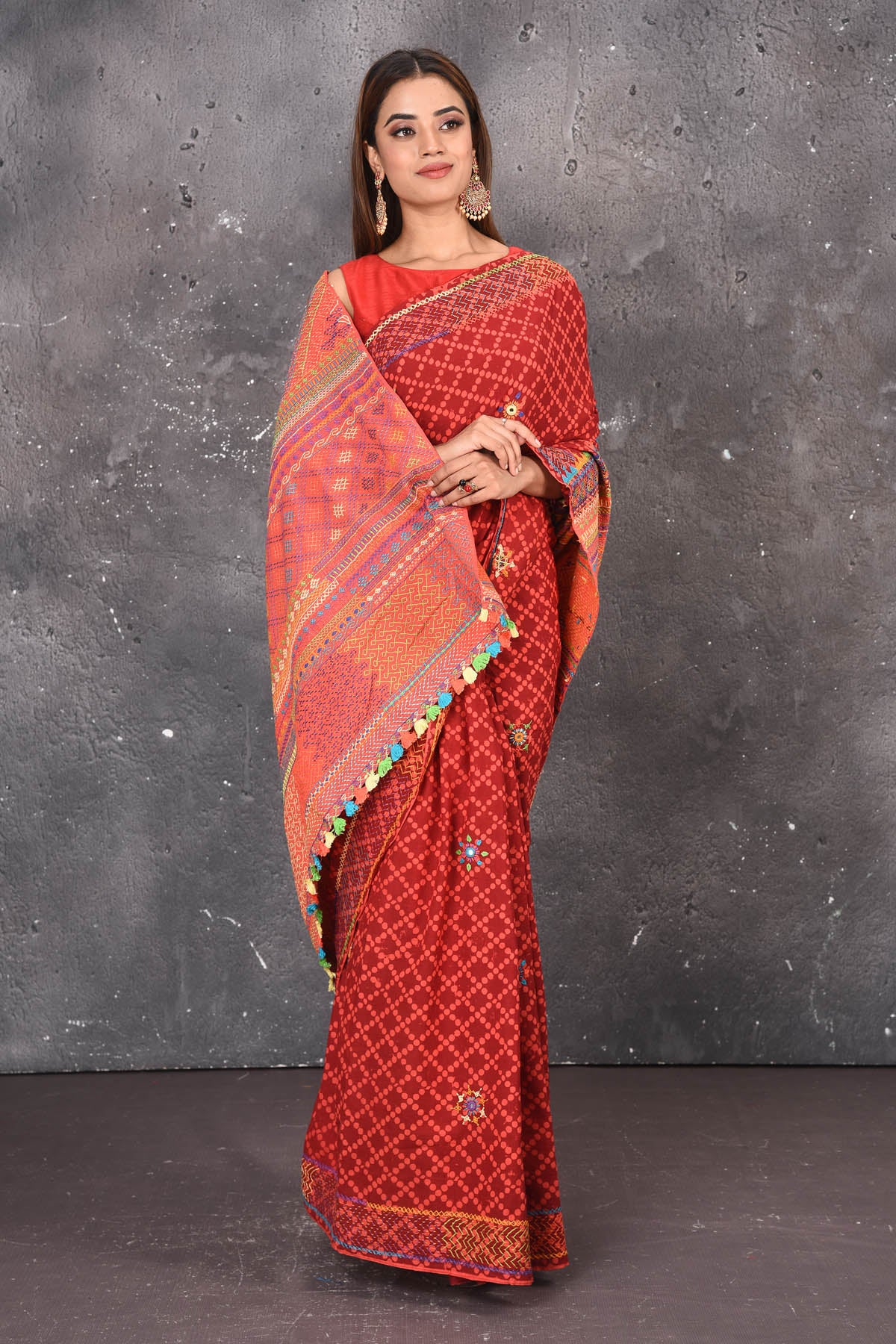 Shop this classy red hand painted madhubani cotton saree online in USA. Perfect to be worn as part of your everyday work wear, with this hand-painted red Madhubani saree, elegance meets traditional. Add this designer Lambani embroidery designer saree with colored tassels to your collection from Pure Elegance Indian Fashion Store in USA.- Full view with Wrapped Pallu.