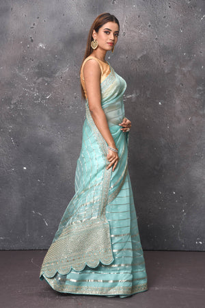 Buy this exquisite firozi blue saree in organza with striped print and silver embroidered border online in USA which is made of organza fabric and lightweight. This organza Saree is beautified with printed work and latest trend. Ideal for casual, kitty parties, stylish accessories. Shop this from Pure Elegance Indian fashion store in USA.-Side view.