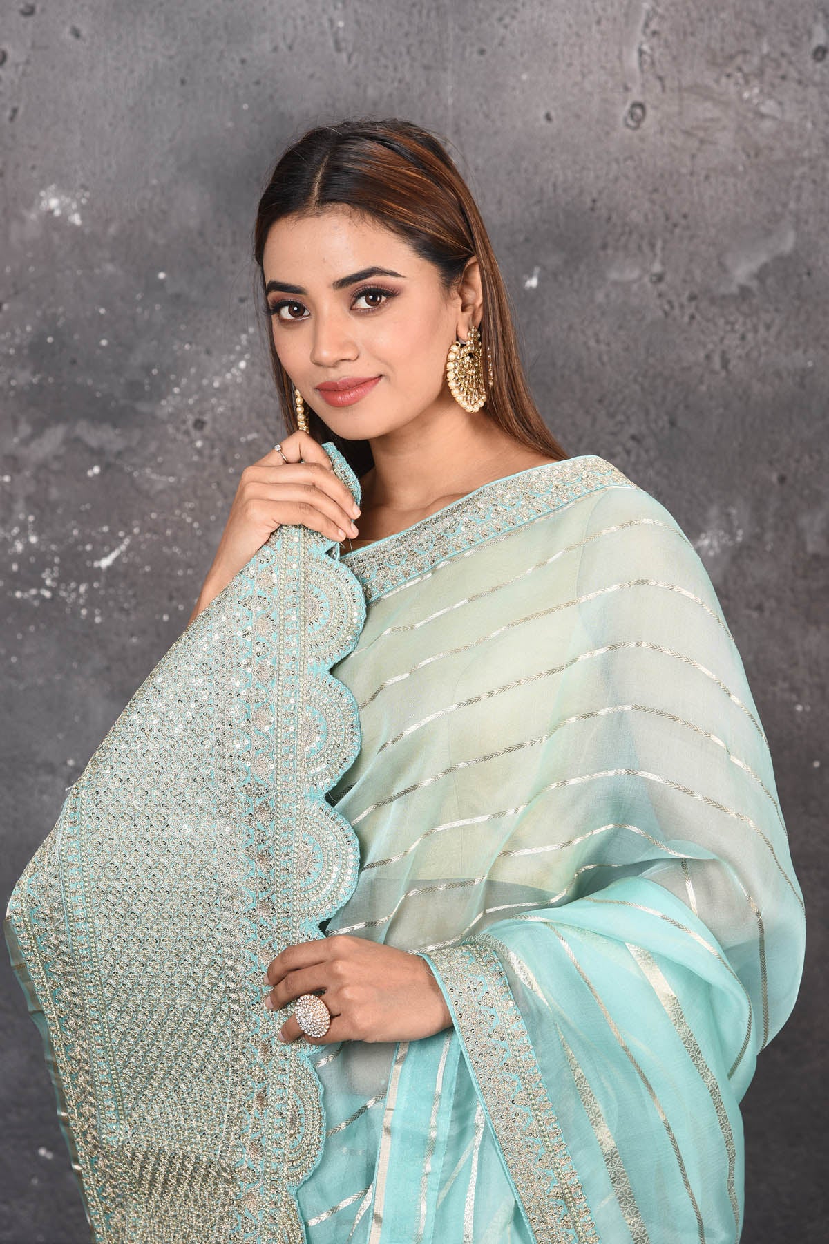 Buy this exquisite firozi blue saree in organza with striped print and silver embroidered border online in USA which is made of organza fabric and lightweight. This organza Saree is beautified with printed work and latest trend. Ideal for casual, kitty parties, stylish accessories. Shop this from Pure Elegance Indian fashion store in USA.- Close up with wrapped pallu.