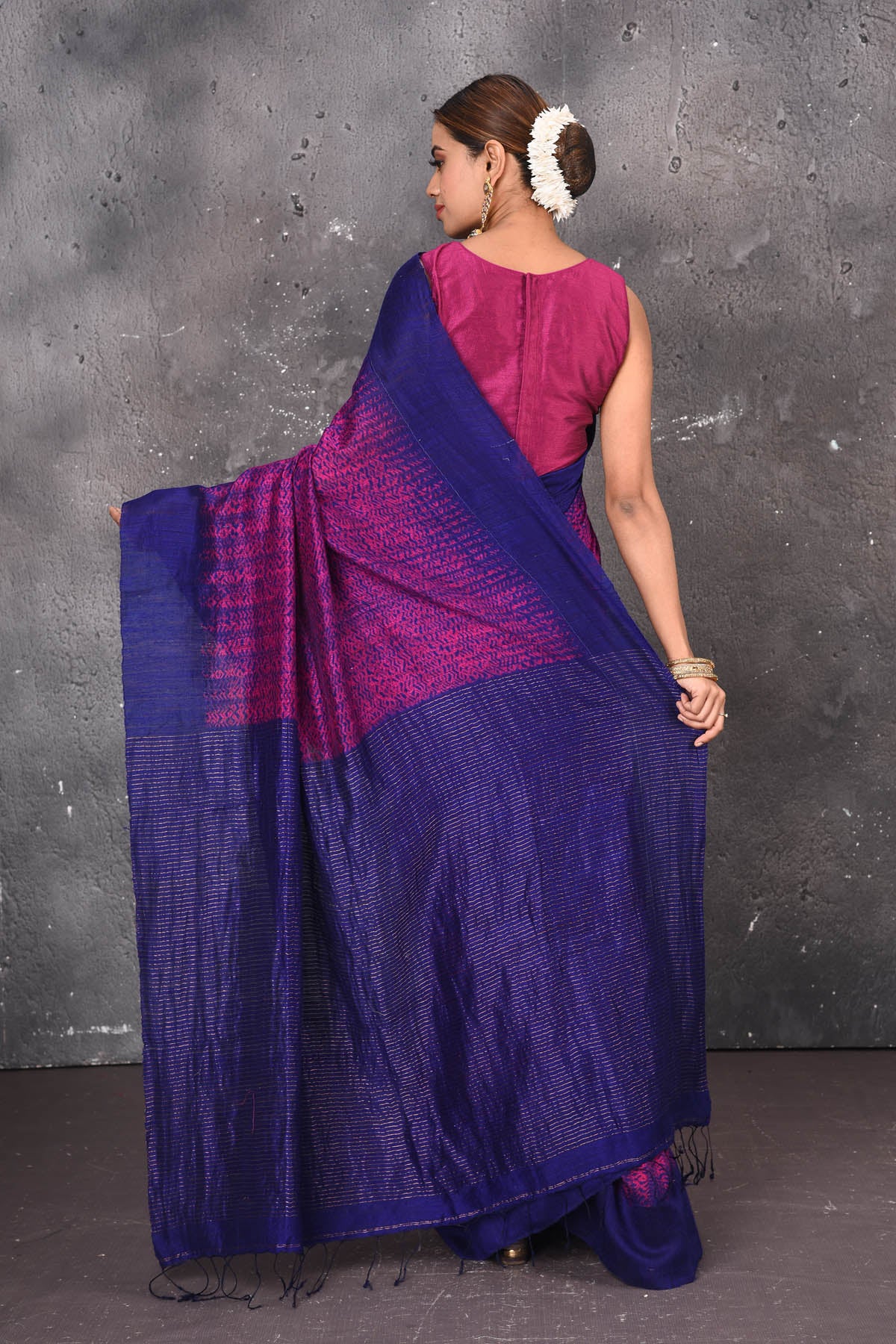Shop this elegant blue-pink handloom shibori tussar saree online in USA which is handcrafted from fine silk tussar fabric, this tie and dye saree brings out the nature of flow. You can pair this beautiful shibori print with minimal jewellery for a casual day outfit. Add this plain shibori saree to your collection from Pure Elegance Indian fashion store in USA.- Back view with open pallu.