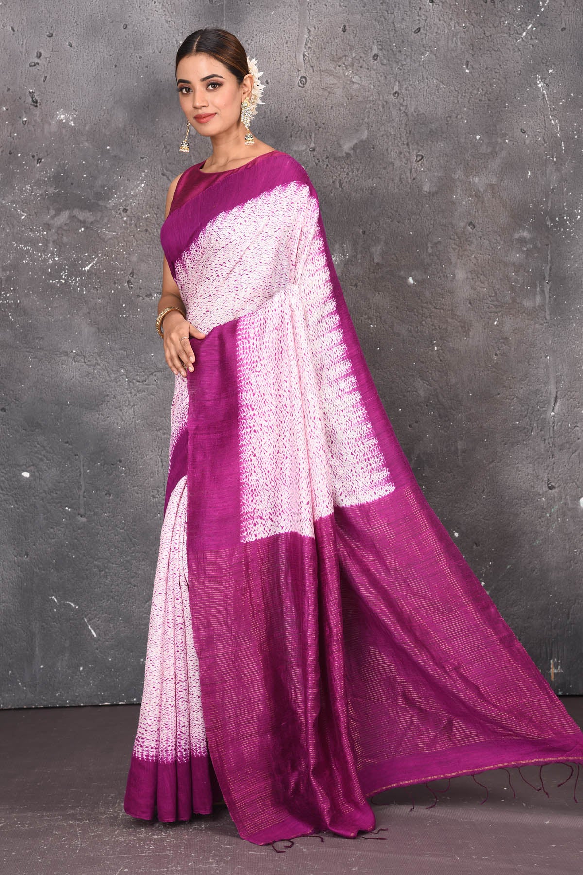 Shop this elegant offwhite-purple handloom shibori tussar saree online in USA which is handcrafted from fine silk tussar fabric, this tie and dye saree brings out the nature of flow. You can pair this beautiful shibori print with minimal jewellery for a casual day outfit. Add this plain shibori saree to your collection from Pure Elegance Indian fashion store in USA.- Side view with open pallu.