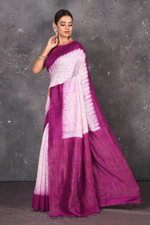Shop this elegant offwhite-purple handloom shibori tussar saree online in USA which is handcrafted from fine silk tussar fabric, this tie and dye saree brings out the nature of flow. You can pair this beautiful shibori print with minimal jewellery for a casual day outfit. Add this plain shibori saree to your collection from Pure Elegance Indian fashion store in USA.-Side view.