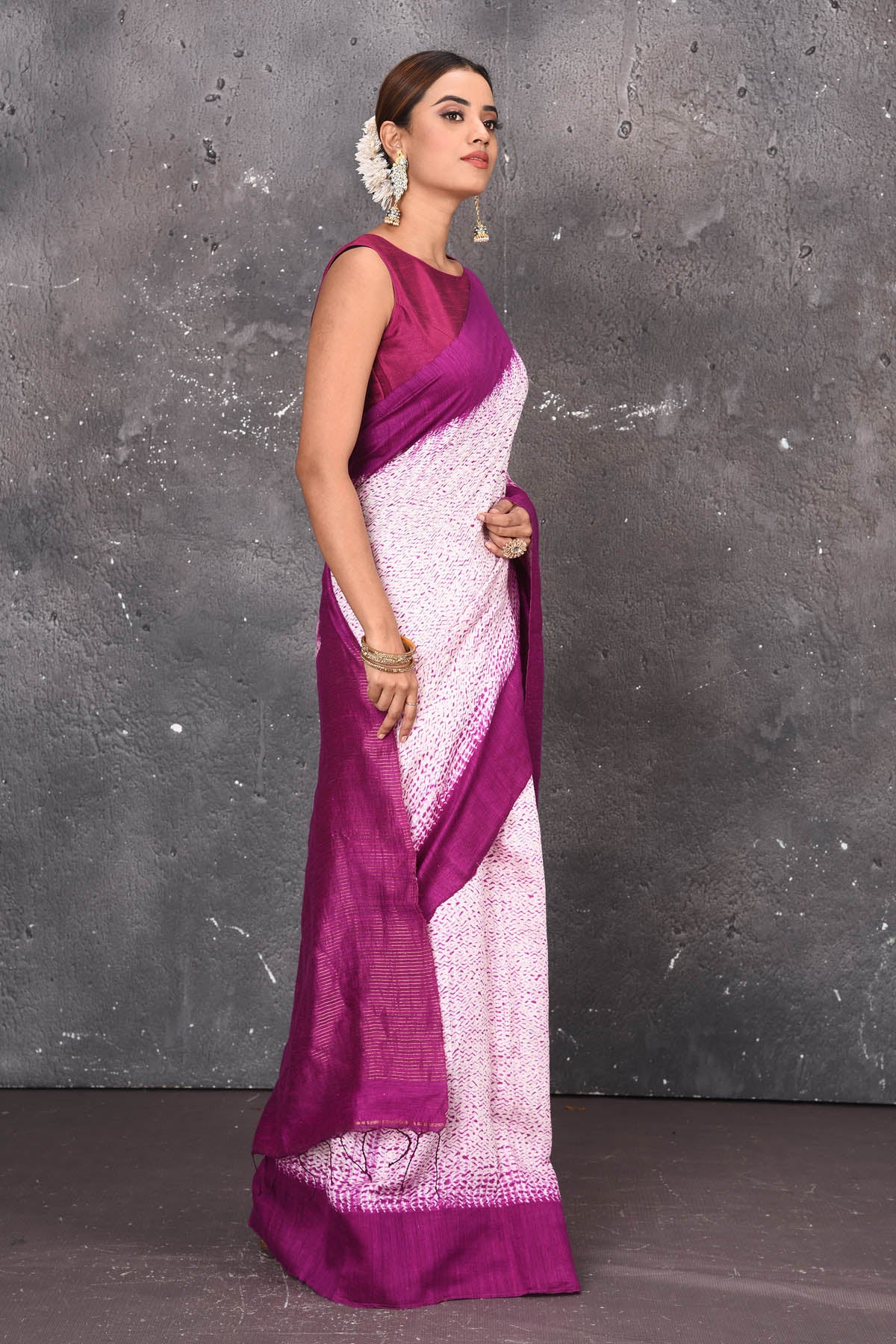Shop this elegant offwhite-purple handloom shibori tussar saree online in USA which is handcrafted from fine silk tussar fabric, this tie and dye saree brings out the nature of flow. You can pair this beautiful shibori print with minimal jewellery for a casual day outfit. Add this plain shibori saree to your collection from Pure Elegance Indian fashion store in USA.-Side view with wrapped pallu.
