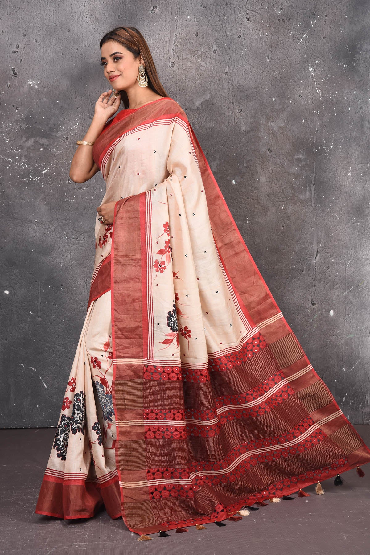 Buy this elegant offwhite-red pure tussar saree with floral embroidered hand cutwork border online in USA which is handcrafted from fine silk tussar fabric, this tie and dye saree brings out the nature of flow. You can pair this beautiful floral embroidered print saree with minimal jewellery for a casual day outfit. Add this pure tussar saree to your collection from Pure Elegance Indian fashion store in USA.-Side view with open pallu.