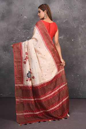 Buy this elegant offwhite-red pure tussar saree with floral embroidered hand cutwork border online in USA which is handcrafted from fine silk tussar fabric, this tie and dye saree brings out the nature of flow. You can pair this beautiful floral embroidered print saree with minimal jewellery for a casual day outfit. Add this pure tussar saree to your collection from Pure Elegance Indian fashion store in USA.-Back view with open pallu.