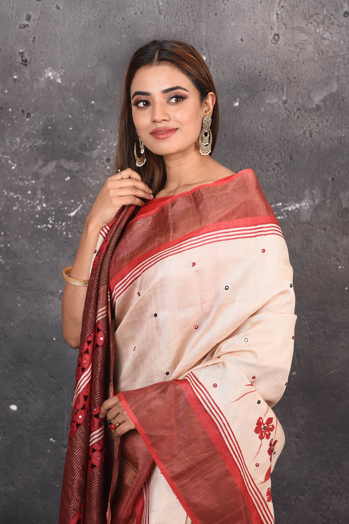 Buy this elegant offwhite-red pure tussar saree with floral embroidered hand cutwork border online in USA which is handcrafted from fine silk tussar fabric, this tie and dye saree brings out the nature of flow. You can pair this beautiful floral embroidered print saree with minimal jewellery for a casual day outfit. Add this pure tussar saree to your collection from Pure Elegance Indian fashion store in USA.-Close up.