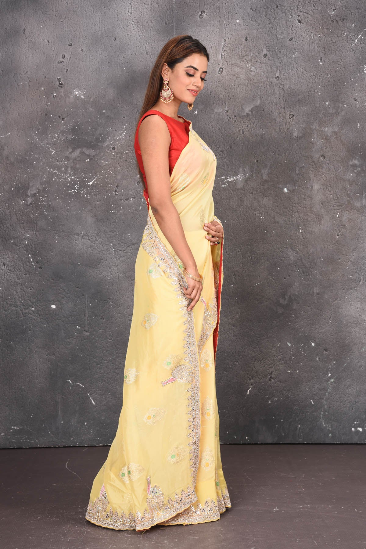 Buy this elegant lemon yellow gota patti mirror embroidered soft organza silk designer saree online in USA with beautiful peacock design threadwork, gota patti leaves and dazzling cut dana and mirror work details. Mirror bootis are scattered all over the saree to match the brightness of the happy look. Add this designer sari to your collection from Pure Elegance Indian fashion store in USA.-Side view.