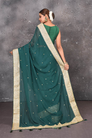 Buy exquisite pine green georgette banarasi designer saree with golden heavy Border online in USA which has crafted by skilled weaver of Banaras with elegance and grace, this saree is definitely the epitome of beauty and a must have in your collection. Buy designer handwoven banarasi georgette sari with any blouse from Pure Elegance Indian saree store in USA.-Back view with open pallu.