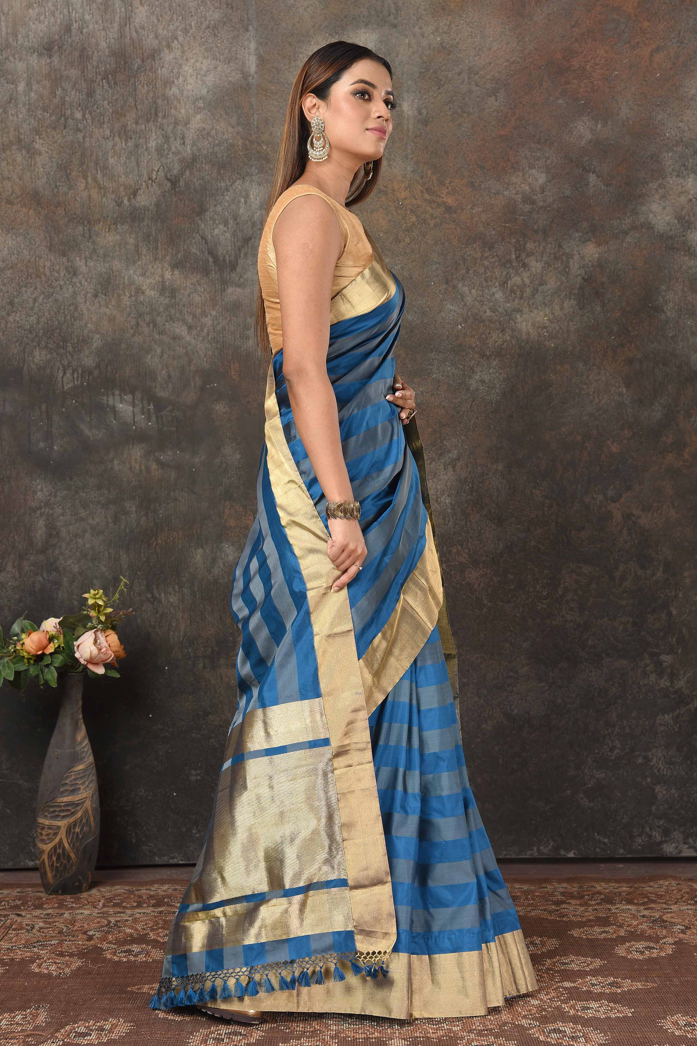 Shop stunning blue grey stripes Banarasi Mashru silk saree online in USA with golden border. Radiate elegance on special occasions in exquisite designer sarees, handwoven sarees, georgette sarees, embroidered sarees, Banarasi saree, pure silk saris, tussar sarees from Pure Elegance Indian saree store in USA.-side