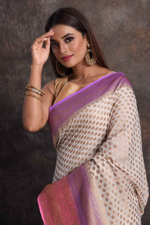 Shop beautiful cream georgette Banarasi saree online in USA with pink and purple border, Be a vision of ethnic elegance on festive occasions in beautiful designer sarees, silk sarees, handloom sarees, Kanchipuram silk sarees, embroidered sarees from Pure Elegance Indian saree store in USA. -closeup