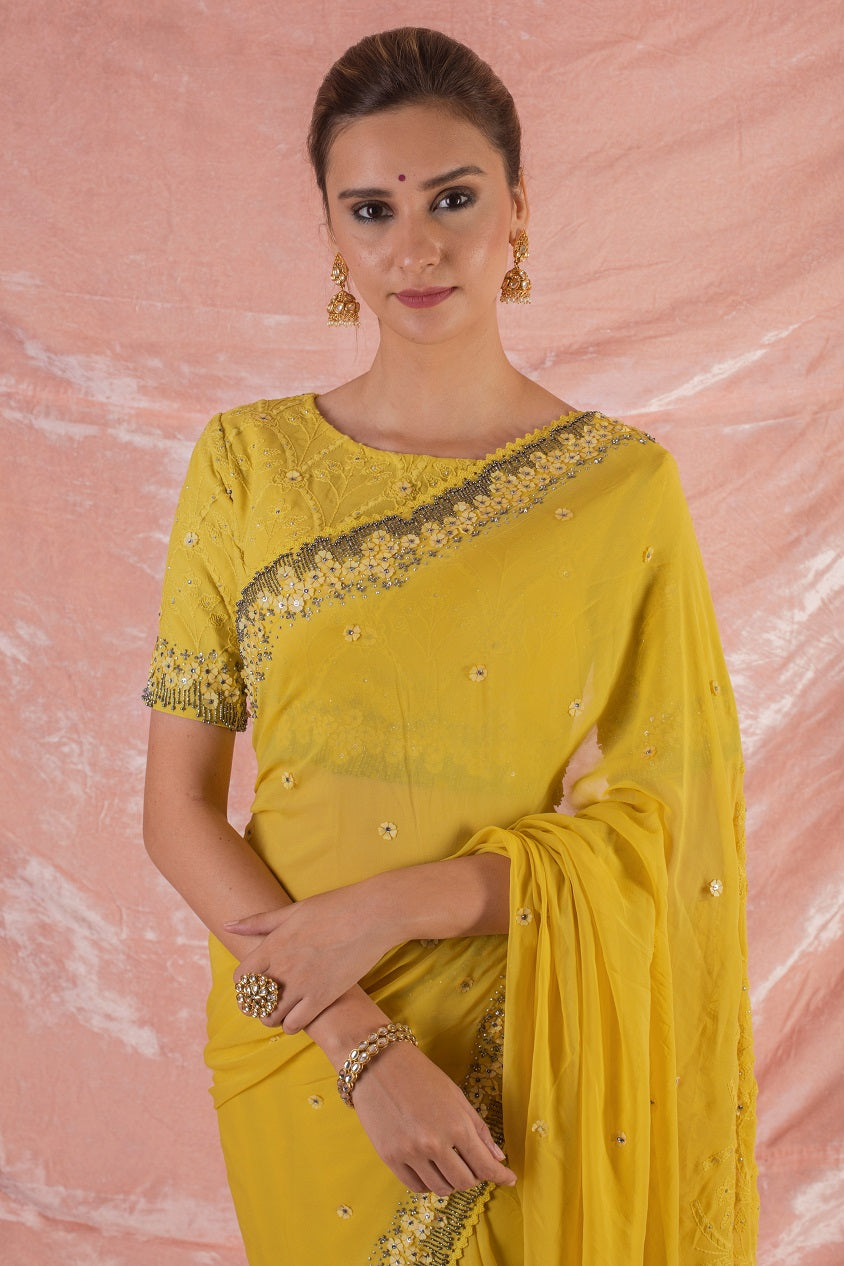 Buy beautiful yellow embroidered georgette saree online in USA.Saree crafted with fine embroidery and simple grey/yellow border.Golden blouse has detailed border around waist and sleeves. Be the talk of parties and weddings with exquisite designer sarees from Pure Elegance Indian clothing store in USA.Shop online now.-close up