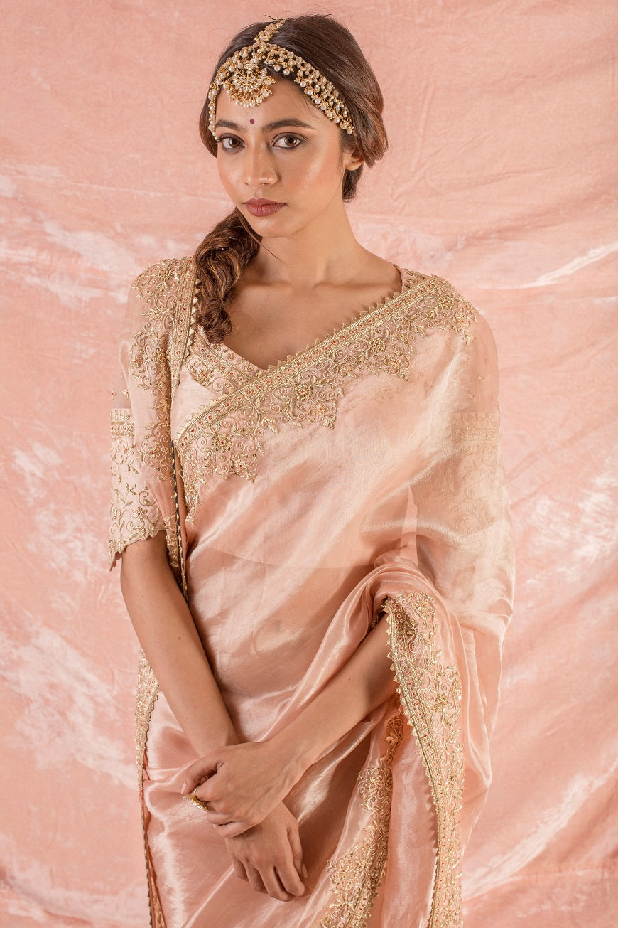 Buy beautiful pastel pink embroidered tissue saree with matching blouse online in USA. Saree crafted with fine embroidery and heavy gold border. Blouse is of U shape with classic design. Be the talk of parties and weddings with exquisite designer sarees from Pure Elegance Indian clothing store in USA.Shop online now.-close up