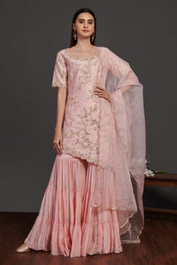 Shop stunning powder pink embroidered sharara suit online in USA with dupatta. Make a fashion statement on festive occasions and weddings with designer suits, Indian dresses, Anarkali suits, palazzo suits, designer gowns, sharara suits from Pure Elegance Indian fashion store in USA.-front