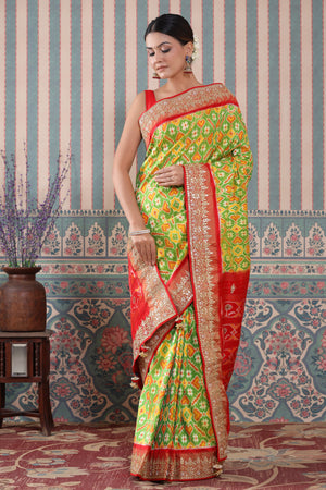 Buy green Patola silk sari online in USA with red embroidered border. Make a fashion statement at weddings with stunning designer sarees, embroidered sarees with blouse, wedding sarees, handloom sarees from Pure Elegance Indian fashion store in USA.-front