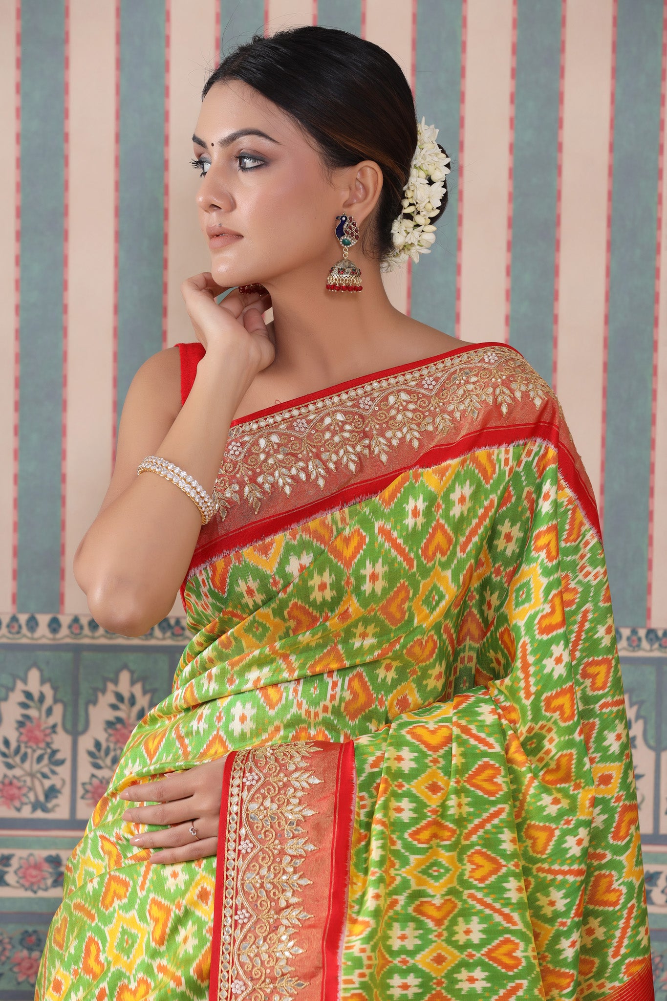 Buy green Patola silk sari online in USA with red embroidered border. Make a fashion statement at weddings with stunning designer sarees, embroidered sarees with blouse, wedding sarees, handloom sarees from Pure Elegance Indian fashion store in USA.-closeup