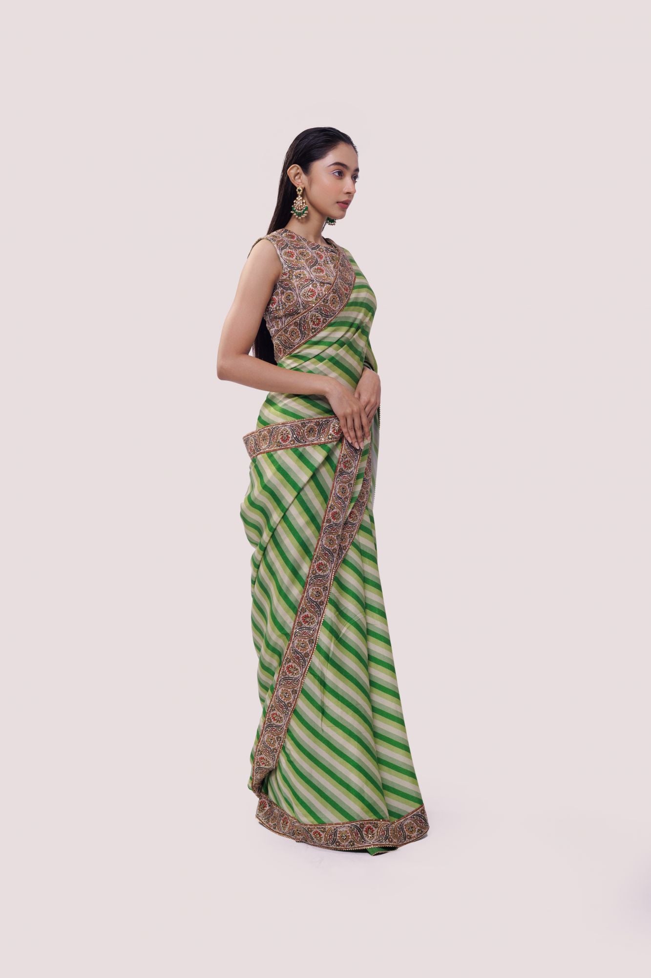 Shop an alluring green satin Saree featuring stripe print and aari work is a perfect choice for parties! It comes with a designer sleeveless saree blouse. Make a fashion statement at weddings with stunning designer sarees, embroidered sarees with blouses, wedding sarees, and handloom sarees from Pure Elegance Indian fashion store in the USA.