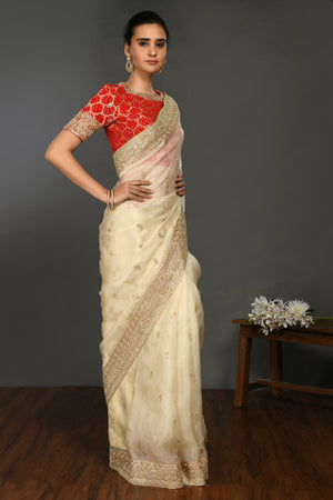 Buy cream hand embroidered organza sari online in USA with red bandhej blouse. Make a fashion statement on festive occasions and weddings with designer sarees, designer suits, Indian dresses, Anarkali suits, palazzo suits, designer gowns, sharara suits, embroidered sarees from Pure Elegance Indian fashion store in USA.-saree