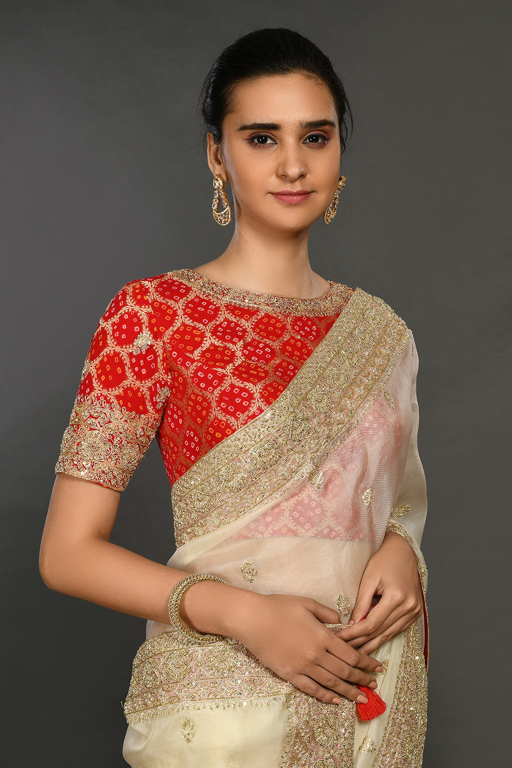 Buy cream hand embroidered organza sari online in USA with red bandhej blouse. Make a fashion statement on festive occasions and weddings with designer sarees, designer suits, Indian dresses, Anarkali suits, palazzo suits, designer gowns, sharara suits, embroidered sarees from Pure Elegance Indian fashion store in USA.-closeup